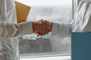 Two Medicare agents shaking hands, symbolizing a strong professional referral network for generating Medicare referral leads.